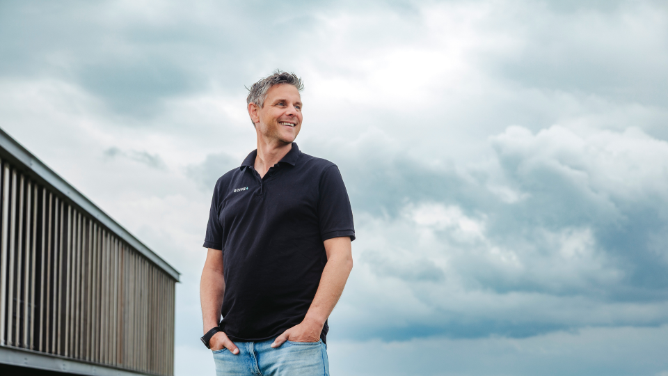 Trotse glimlachende man met bewolkte lucht in de achtergrond