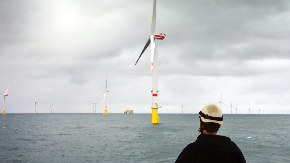 Beeld op zee van windmolen + man